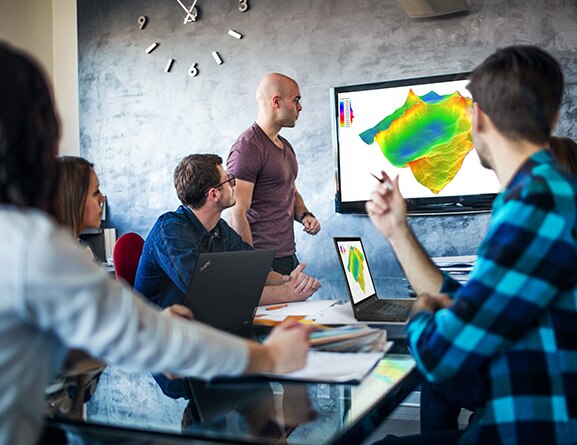 Group of people in a conference room with Lenovo ThinkPad P15 Gen 2 mobile workstations and a wall display mirroring one of the laptops.